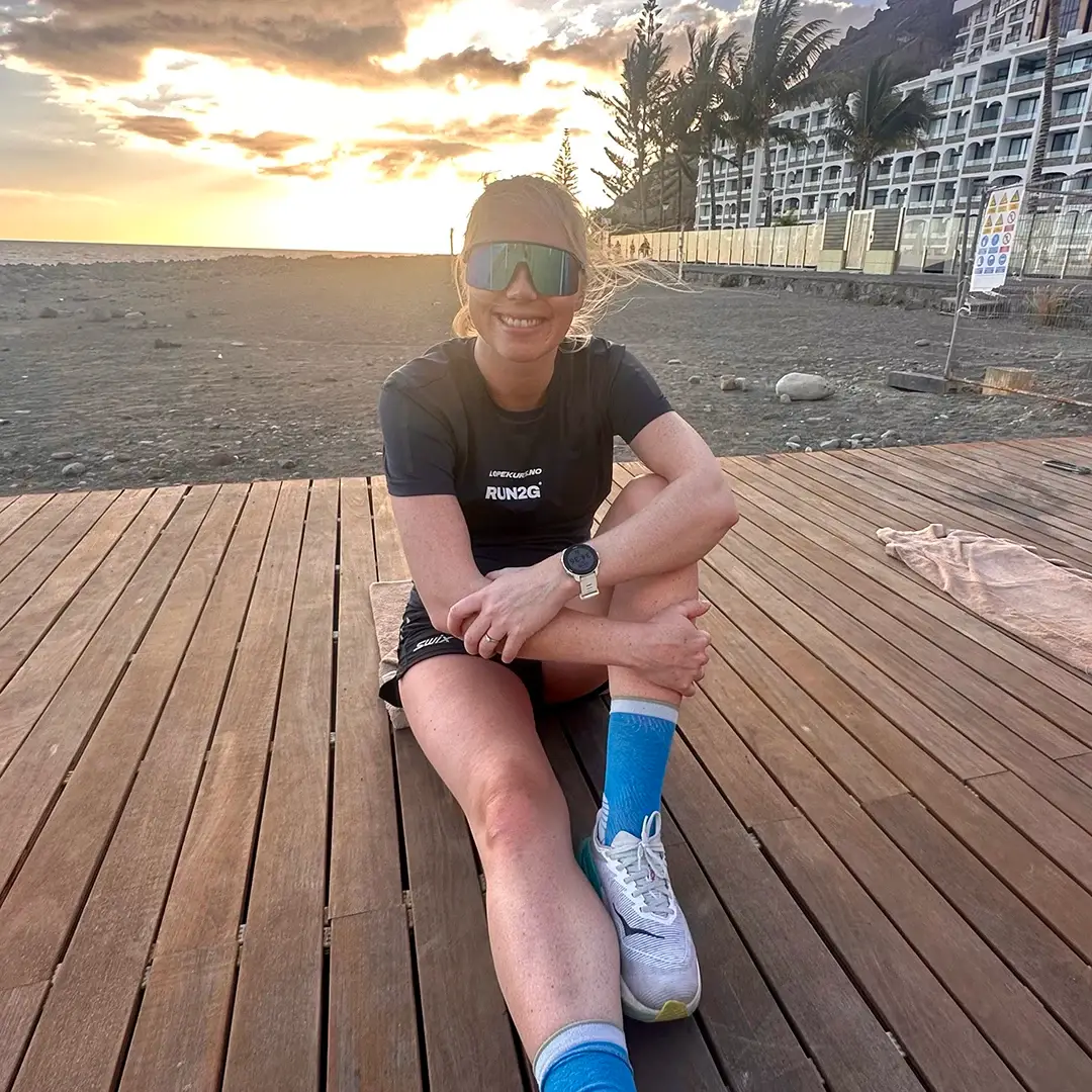 Veronica Undseth fra Løpekurs.no og Run2gether sitter og slapper av etter en løpetur i solnedgangen på strandpromenade i Spania.

